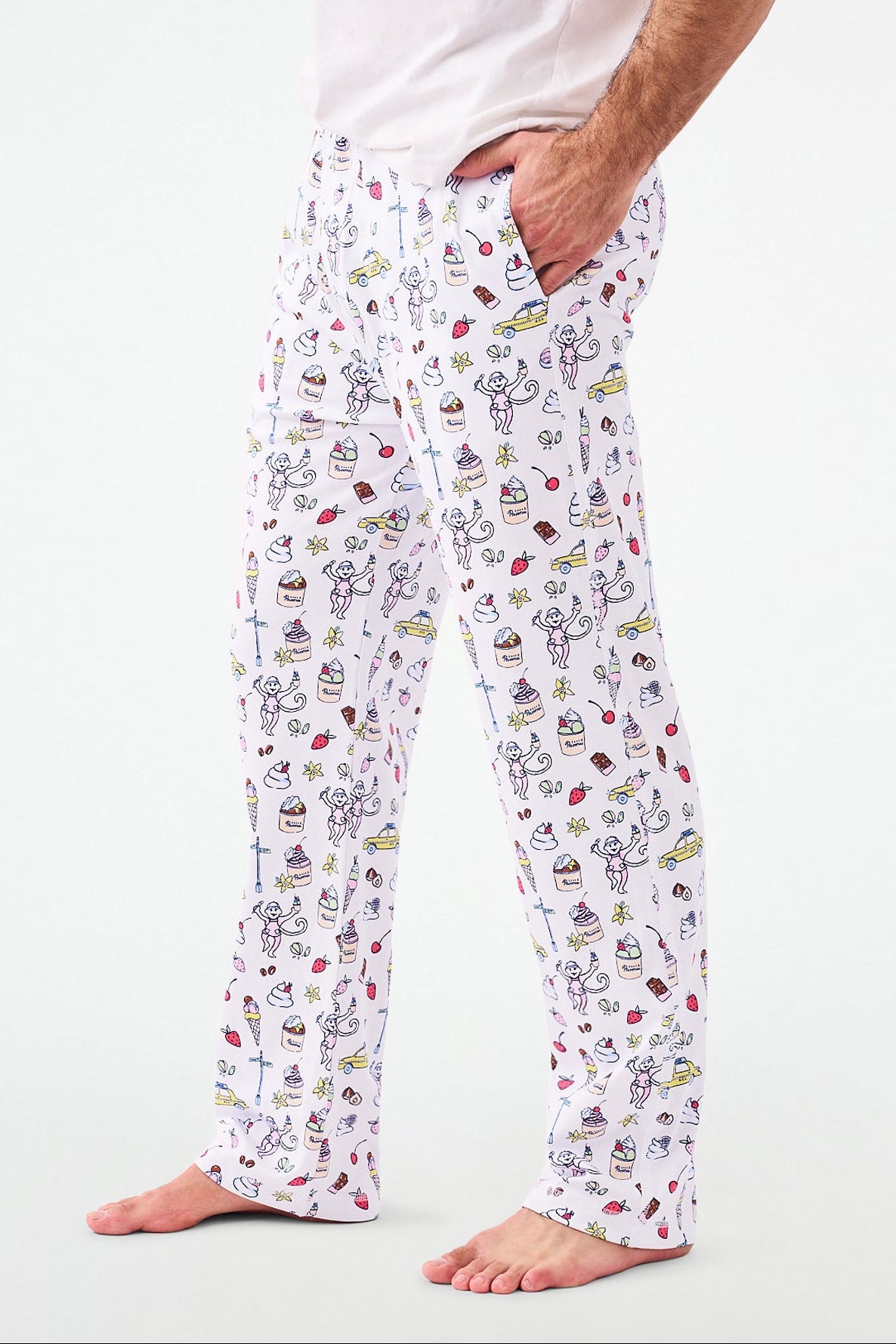 A man wearing white pajama pants with a multicolored ice cream and sweet treats print. view 1