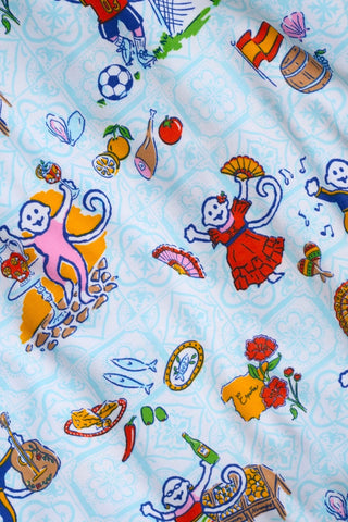 Colorful fabric featuring playful monkeys in various outfits and activities, such as dancing, eating, and playing instruments, surrounded by flowers and decorative objects on a light blue patterned background.