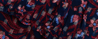 Navy blue fabric with a floral pattern in shades of red and blue, featuring metallic silver woven accents and a gathered seam.