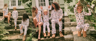 Three people in matching pajamas sit and play on stone steps outdoors; a child smiles while holding a tree branch. All appear happy and relaxed, enjoying a sunny day together.