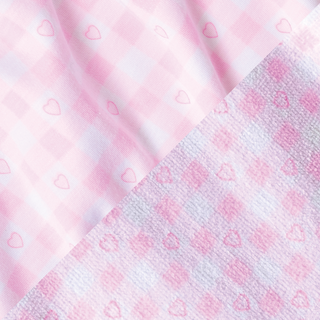 A close-up of two pink gingham fabrics side by side, both featuring tiny heart outlines. The left fabric appears smoother while the right has a textured, towel-like surface.