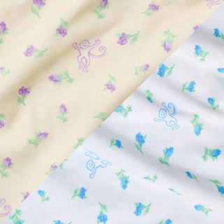 Yellow and white fabric with a diagonal seam, featuring small cartoon monkeys and purple or blue flowers scattered across the surface.