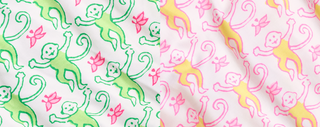 Patterned fabric with simple line drawings of monkeys and flowers; left side features green monkeys and pink flowers, right side has yellow monkeys and pink flowers, both on a white background.