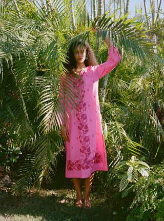 Woman in a pink dress standing among tropical plants