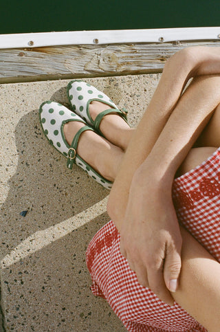 The FLABELUS Polka Dot Pierre is a cream Mary Jane flat with green trim, a green strap featuring a gold buckle, and polka dots—part of the Flabelus collaboration.