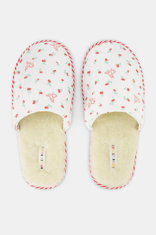 The Mini Monkey Blossom Quilted Slipper by Roller Rabbit features a white quilted design with a floral pattern, red trim, and a soft beige fuzzy lining, displayed on a plain white background.
