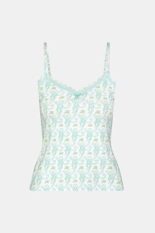 A woman with long blonde hair is wearing the Roller Rabbit Monkey Perry Cami pajama set. The light blue and white cotton-modal set features thin straps, a scalloped lace trim neckline, and matching loose pants. She stands, smiling slightly.