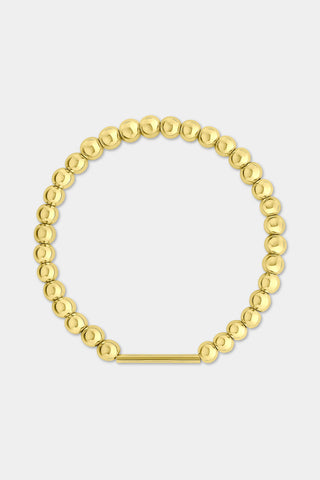 The Roller Rabbit Ladybug Charm is a small golden accessory featuring raised dots and a convenient loop at the top for attaching to jewelry, making it perfect for adding to a charm bracelet. It is showcased against a light gray background.