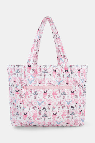 Wearing matching pink and white floral shorts and top, a person stands by lockers holding the Roller Rabbit Monkey Pirouette Quilted Tote, paired with white socks and blue sneakers.