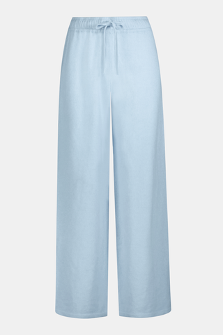 A woman poses with her arms crossed, wearing an icy blue AFFINA Moxie Cardigan with pearl-like buttons and matching drawstring pants.