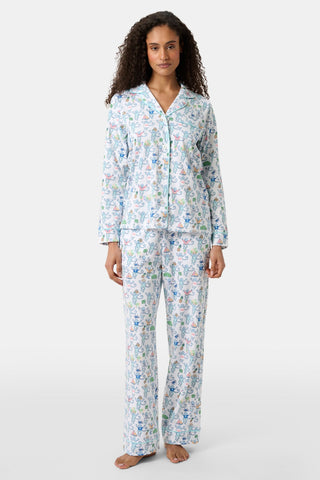 A woman stands barefoot in the Charleston Monkey Long Sleeve Polo Pajamas, a matching Pima cotton sleepwear set with a playful monkey print. The women's pajamas feature a long-sleeve, button-up top and full-length pants.