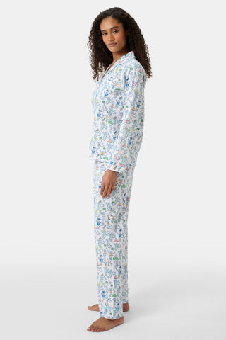 A woman with curly hair stands barefoot, wearing Charleston Monkey Long Sleeve Polo Pajamas. She faces left and looks at the camera, highlighting these stylish women's pajamas against a plain white background.