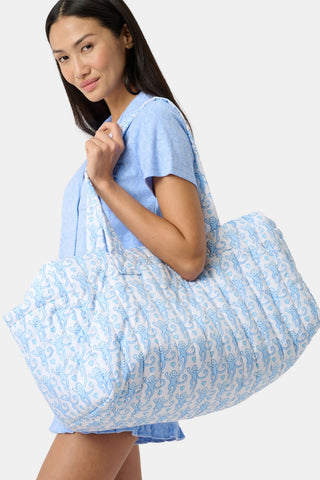 The Roller Rabbit Lovely Monkey Quilted Weekender is a rectangular travel bag with two handles, crafted from nylon, and features a white background with a light blue abstract swirl pattern.