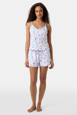 A person wearing Roller Rabbit’s Mens Monkey On The Vineyard Simon Pant—white Pima cotton pajama pants with a colorful, playful print—stands barefoot against a plain background.