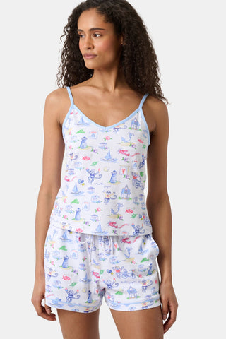 A person wearing Roller Rabbit’s Mens Monkey On The Vineyard Simon Pant—white Pima cotton pajama pants with a colorful, playful print—stands barefoot against a plain background.