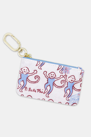 The Roller Rabbit Pi Beta Phi Monkey Coin Pouch is a small zippered pouch made from water-resistant cotton canvas, featuring playful purple monkeys, blue accents, and “Pi Beta Phi” text on white fabric, and finished with a gold keyring clip.