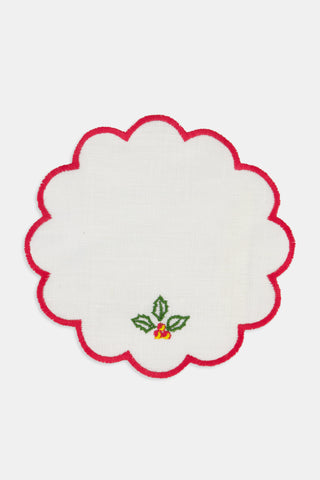 Seasons Soiree Scallop Cocktail Napkin Set Of 4: four round 100 linen napkins with scalloped red edges, each featuring a different embroidered Christmas icon: a tree, holly, a candy cane, and bells.