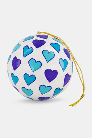 A hand-painted white spherical Pop Hearts ornament by Roller Rabbit, decorated with a repeating pattern of light and dark blue hearts, hanging from a gold string.