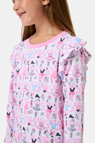 The Roller Rabbit Kids Monkey Pirouette Isa Dress features long sleeves, a pink collar, and ruffle shoulders. Crafted from soft Pima Cotton for all-day comfort, this dress showcases a playful pattern of cartoon monkeys dancing pirouettes on a white background.