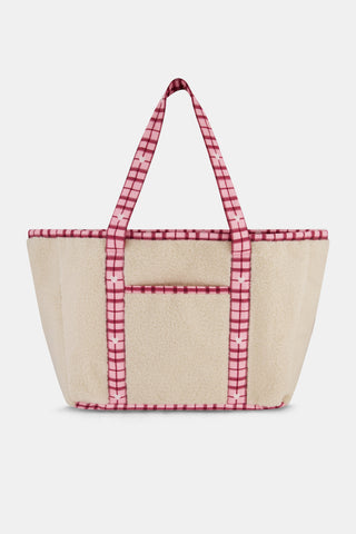 A person holds a beige sherpa Plaid Hearts Sherpa Tote with pink plaid handles and trim, coordinating with a matching pink plaid heart patch on their sweatpants.