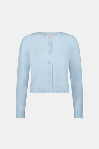 A woman poses with her arms crossed, wearing an icy blue AFFINA Moxie Cardigan with pearl-like buttons and matching drawstring pants.
