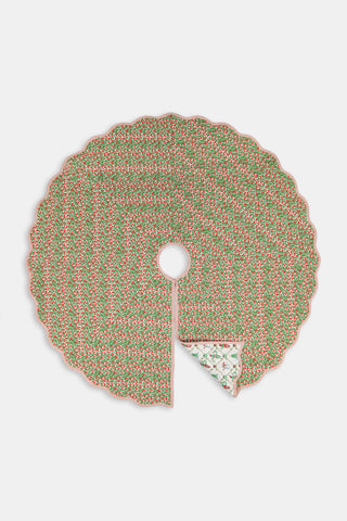 Round SAPPHIRE Deck The Halls/Holly Berry Tree Skirt featuring a white quilted pattern of holly, snowmen, and dancing elves with a scalloped pink edge, partially folded to reveal an 80s printed green and red holly-patterned underside.