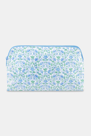The Roller Rabbit Garden Gate Floral Makeup Bag features a rectangular zippered design with a blue and green floral pattern on a white cotton canvas background, photographed against a simple light backdrop. Perfect for organizing your beauty essentials at home or while traveling.