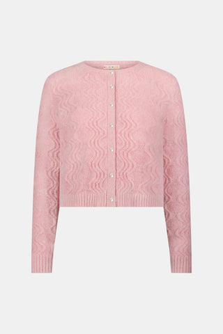 A woman wearing an AFFINA Wave Knit Moxie Cardigan in light pink over a dark green pleated skirt with a pink floral print.