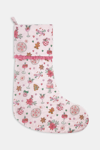SAPPHIRE Seasons Soiree Quilted Ruffle Stocking in pale pink, featuring a pattern of poinsettias, gingerbread men, and holiday treats, finished with a ruffled trim at the cuff.