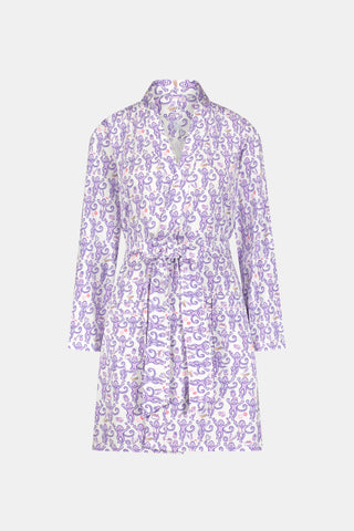A woman smiles while wearing the TEXPIMA Get Ready With Me Blake Robe, featuring a knee-length cut and a purple and pink paisley pattern, tied at the waist, against a plain white background.