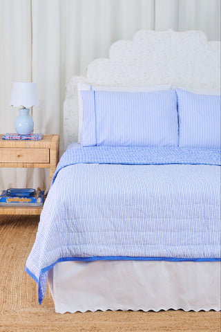 Bed with blue bedding and pillows in a bedroom setting.