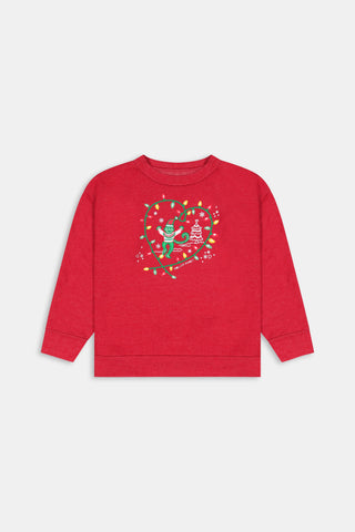 A child wears a Kids Deck The Halls Andie Sweatshirt featuring a heart made of festive lights, a cartoon monkey, and a Christmas tree graphic, paired with patterned leggings showing elves and snowmen.