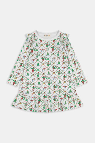 A young girl wears a Kids Deck The Halls Isa Dress, a long-sleeved Pima Cotton holiday dress featuring a white background with a festive monkey print of snowmen and Christmas trees.
