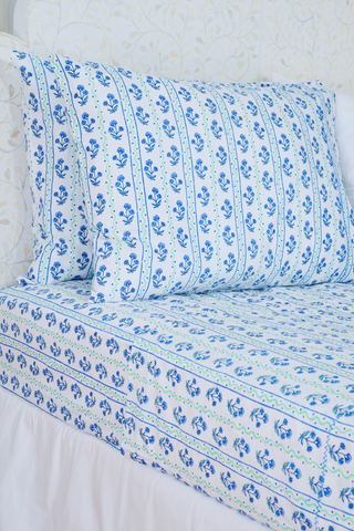 The Rosa Wavy Stripe Sheet Set by Roller Rabbit features a white sheet with blue floral print and green wavy stripes, ideal for twin XL beds or anyone seeking stylish cotton bedding.
