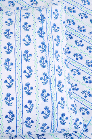 The Rosa Wavy Stripe Sheet Set by Roller Rabbit features a white sheet with blue floral print and green wavy stripes, ideal for twin XL beds or anyone seeking stylish cotton bedding.