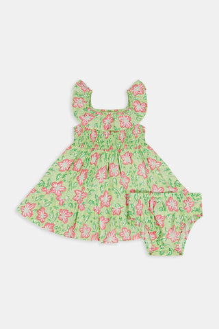 The Kids Verdant Floral Ryan Dress by Roller Rabbit is a green dress for little ones, showcasing pink and white hibiscus flowers in a floral block print. It features ruffled sleeves, a matching diaper cover, and is crafted from soft cotton for comfortable pullover wear.