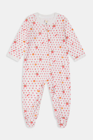 A woman in the Roller Rabbit Autumn Hearts Fiora Pajamas and brown boots sits on a wooden fence, smiling and resting one arm on a tree branch in a sunny outdoor setting, evoking the coziness of fall sleepwear.