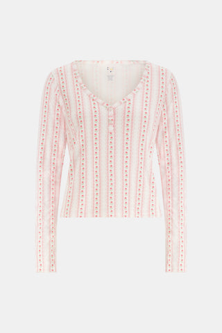 A woman smiles while wearing the Roller Rabbit Daisy Heart Stripe Jessie Long Sleeve Tee, a soft Pima cotton top adorned with pink and red daisies, paired with matching pajama bottoms, against a plain white background.