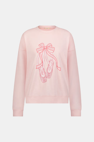 A person with long blonde hair in a ballet slipper-pink Roller Rabbit Monkey Pirouette Andie Sweatshirt holds patterned folders in front of white lockers.