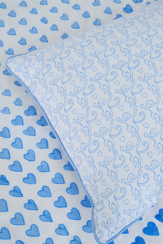 The Monkey Decorative Pillow by Roller Rabbit is a square cotton throw pillow with a light blue background, abstract swirling blue lines, and neatly finished edges in darker blue piping—an elegant addition to any space.