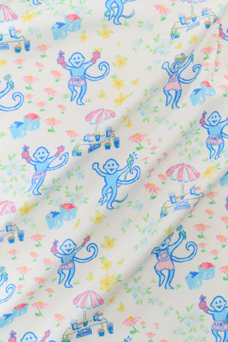 The Kids May Flowers Noa Set by Roller Rabbit features a playful print with blue monkeys in pink shorts, flowers, and bright objects on a light background—perfect for fun and cozy moments.