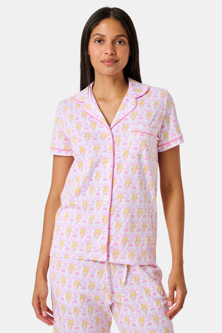 Introducing the Monkey Fiora Pajamas from Roller Rabbit—crafted from fabric adorned with a delightful pattern of pink and yellow monkeys with curled tails and smiling faces, interspersed with tiny leaves on a crisp white background. Perfect for adding playful charm to your sleepwear collection.