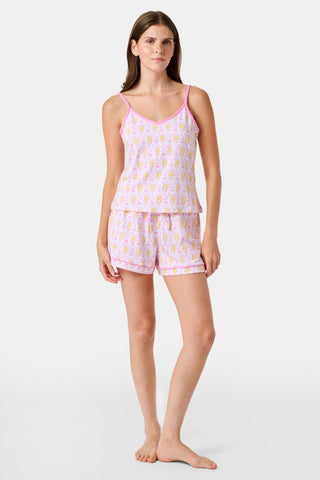 A woman wearing the Roller Rabbit Monkey Mischa Set stands with one hand in her pocket against a plain white background. This pajama set features a light pink flamingo print camisole and matching shorts, crafted from soft Pima cotton for comfort and style in women’s sleepwear.