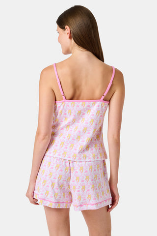 A woman wearing the Roller Rabbit Monkey Mischa Set stands with one hand in her pocket against a plain white background. This pajama set features a light pink flamingo print camisole and matching shorts, crafted from soft Pima cotton for comfort and style in women’s sleepwear.