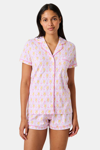 Introducing the Monkey Fiora Pajamas from Roller Rabbit—crafted from fabric adorned with a delightful pattern of pink and yellow monkeys with curled tails and smiling faces, interspersed with tiny leaves on a crisp white background. Perfect for adding playful charm to your sleepwear collection.