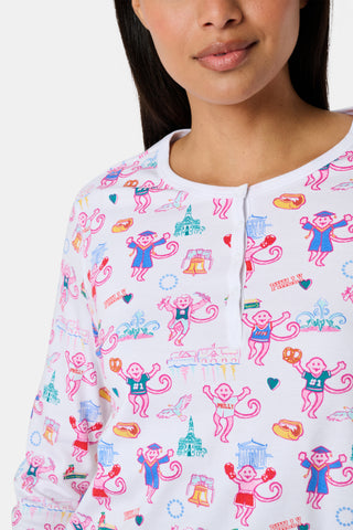 A woman stands barefoot wearing a matching long-sleeve Roller Rabbit Philly Monkey Pajamas set featuring a colorful floral and animal print on a white background.