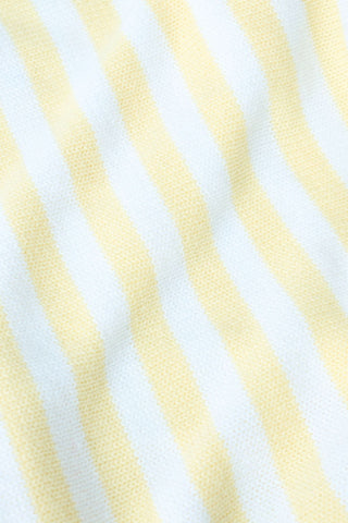 A young woman with light skin and long brown hair wears the Roller Rabbit Striped Rocio Sweater, a pastel yellow, lightweight cotton knit with a wide V-neck and collar. She pairs it with matching drawstring pants and gazes slightly to the side.