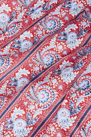 Close-up of the Provencal Stripe Casa Kurta by Roller Rabbit, showing red cotton sateen fabric with white and blue floral patterns, decorative stripes, slight folds, and a textured look.