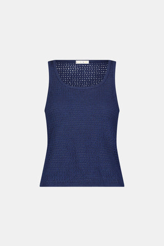 A woman wears the Roller Rabbit Pointelle Sasha Sweater Tank in navy with a textured open-weave design, paired with white shorts featuring blue floral prints. She is shown from shoulders to waist, looking slightly to the side.