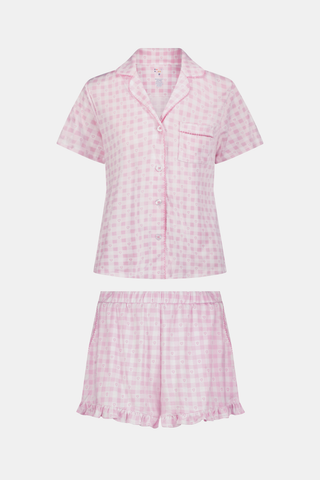 The Gingham Hearts Wyatt Polo Pajamas by Roller Rabbit are a pink and white gingham short-sleeve pajama set, featuring a button-up shirt with chest pocket and matching shorts with a ruffled hem, all crafted from soft Pima cotton. This set is shown on a white background.